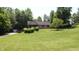 Lush front lawn featuring a charming brick house with a covered front porch and detached shed at 11059 W Old Nashville Rd, Columbus, IN 47201