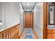 Hallway featuring wood railing, decorative pendant lights, and a blue pattern runner rug at 11059 W Old Nashville Rd, Columbus, IN 47201