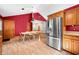 Bright kitchen with stainless steel refrigerator, wood cabinets, dining table and chairs, and red accent wall at 11059 W Old Nashville Rd, Columbus, IN 47201
