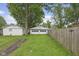 Backyard featuring lush greenery, a fence, and a detached garage at 113 N Munsie St, Indianapolis, IN 46229