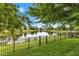 Backyard view of a calm lake surrounded by lush greenery and a secure fence at 12234 Limestone Dr, Fishers, IN 46037