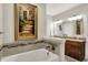 Bright bathroom features a soaking tub, a vanity with granite countertops, and artwork at 15410 Mission Hills Dr, Carmel, IN 46033