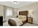 Comfortable bedroom features a tufted headboard, neutral colors, bedside lamps, and a bright window at 15410 Mission Hills Dr, Carmel, IN 46033