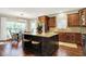 Kitchen with dark island, granite countertops, brown wood cabinets, stainless steel appliances, and view of dining area at 15410 Mission Hills Dr, Carmel, IN 46033