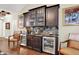 Chic wet bar with dark cabinetry, marble countertops, wine coolers, and decorative art at 15410 Mission Hills Dr, Carmel, IN 46033