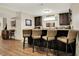 Elegant wet bar with dark cabinets, granite countertops, a mini-fridge, and seating for entertaining at 15410 Mission Hills Dr, Carmel, IN 46033