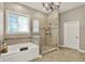 Bathroom featuring a soaking tub, glass shower, and chandelier at 15529 Mission Hills Dr, Carmel, IN 46033