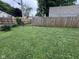 A fenced backyard with mature trees and a grassy lawn, with chain link on one side and wood on the other at 1768 N Lynhurst Dr, Speedway, IN 46224