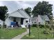 A charming single-story home with a covered porch and an American flag in a mature, tree-lined yard at 1768 N Lynhurst Dr, Speedway, IN 46224
