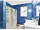 This full bathroom features blue walls, a white vanity, and shower with a plant-themed shower curtain at 26 E Plum St, Anderson, IN 46012