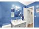 This full bathroom features blue walls, a white vanity, and decorative mirror and lighting at 26 E Plum St, Anderson, IN 46012