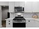 Modern stainless steel gas range and microwave with decorative backsplash and white cabinetry at 2733 Lamar Dr, Whitestown, IN 46075