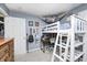 Well-lit bedroom with gray walls featuring a unique bunk bed with a built-in desk and a plush toy hammock at 333 N Windswept Rd, Greenfield, IN 46140