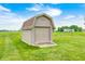 A backyard storage shed with a garage door and stone base in a grassy yard at 333 N Windswept Rd, Greenfield, IN 46140