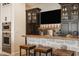 Basement bar area featuring granite countertop, stone accents, dark cabinets, and stainless appliances at 3675 Dartmoor Way, Zionsville, IN 46077