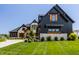 Picture of a stylish home featuring a blend of dark wood and light stone, enhanced by a green lawn at 3675 Dartmoor Way, Zionsville, IN 46077