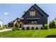 Picture of a stylish home featuring a blend of dark wood and light stone, enhanced by a green lawn at 3675 Dartmoor Way, Zionsville, IN 46077