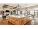 Open-concept kitchen featuring an island, hardwood floors, pendant lighting, and stone fireplace at 3675 Dartmoor Way, Zionsville, IN 46077