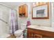 Standard bathroom with wooden vanity, medicine cabinet, and shower with purple curtain at 409 N Sycamore St, Martinsville, IN 46151