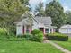 Charming home featuring a red door, well-kept lawn, and mature landscaping, creating a welcoming entrance at 409 N Sycamore St, Martinsville, IN 46151