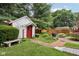 Exterior view of a white shed with red trim and a brick pathway amidst a well-maintained garden at 409 N Sycamore St, Martinsville, IN 46151