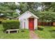 Charming white shed with red trim, surrounded by lush landscaping and greenery at 409 N Sycamore St, Martinsville, IN 46151