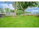 Large backyard featuring mature trees, green grass, a storage shed and ' playground equipment at 4210 Main St, Anderson, IN 46013
