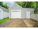 Detached garage with a white door and concrete driveway and a small side entrance for pedestrian access at 4210 Main St, Anderson, IN 46013