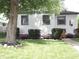 Charming home featuring a landscaped front yard with flowering bushes and a large shade tree at 4445 Kingsley Dr, Indianapolis, IN 46205