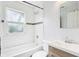 Bathroom with white tiling, window, bath tub, toilet and wood-look sink at 524 S Arlington Ave, Indianapolis, IN 46219