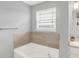 Bright bathroom featuring a bathtub with tiled surround and natural light from a window at 5812 Flat Hill Dr, Indianapolis, IN 46239