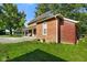 View of the side and back of a red brick house from a lush green lawn at 590 W Washington St, Martinsville, IN 46151