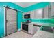 Modern kitchen with grey cabinets, stainless steel appliances, sliding barn door and bright turquoise walls at 590 W Washington St, Martinsville, IN 46151