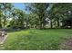 Large backyard surrounded by mature trees and a partial fence at 7141 E Pleasant Run Pkwy S Dr, Indianapolis, IN 46219