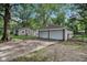 Spacious two-car garage situated near the house, complete with a long driveway and gravel area, surrounded by trees at 7141 E Pleasant Run Pkwy S Dr, Indianapolis, IN 46219
