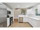 Bright kitchen featuring stainless steel appliances, white cabinetry, and hardwood floors with an open staircase view at 7141 E Pleasant Run Pkwy S Dr, Indianapolis, IN 46219
