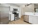 Modern kitchen with stainless steel appliances, white cabinets, and hardwood floors with an open view to the staircase at 7141 E Pleasant Run Pkwy S Dr, Indianapolis, IN 46219