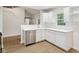 Updated kitchen featuring stainless steel appliances, white cabinets, hardwood floors and view to staircase at 7141 E Pleasant Run Pkwy S Dr, Indianapolis, IN 46219