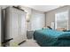 Cozy bedroom featuring a white armoire, closet, comfortable teal quilt, and natural light from the window at 8038 Midlothian Way, Indianapolis, IN 46214