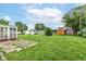 A lush backyard with a spacious lawn, patio, multiple sheds, and mature trees, perfect for outdoor enjoyment at 823 Rustic Rd, Anderson, IN 46013