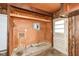 Unfinished basement with vintage wood paneling, concrete floor, and door to exterior; good for storage and laundry at 823 Rustic Rd, Anderson, IN 46013