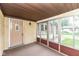 Enclosed porch showcasing a welcoming entrance with a brick accent wall and multiple windows for natural light at 823 Rustic Rd, Anderson, IN 46013