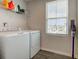 Functional laundry room features a washer, dryer, storage shelf, and a vacuum cleaner; illuminated by a window at 853 Woodbridge Way, Lebanon, IN 46052