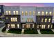 Modern townhome showcasing gray brick and siding, well-lit windows, and manicured landscaping at dusk at 9728 Junction, Fishers, IN 46037
