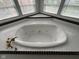 Relaxing jetted tub surrounded by tile, with natural light streaming in from the adjacent windows, is perfect for a spa-like experience at 9985 Ford Valley Ln, Zionsville, IN 46077
