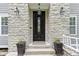 Elegant front door with stone facade, decorative lighting, and planters adding curb appeal at 9985 Ford Valley Ln, Zionsville, IN 46077
