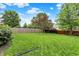 Spacious backyard with green lawn, mature trees, and a wooden fence providing seclusion at 10758 Gettysburg Pl, Carmel, IN 46032
