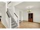 Bright foyer showcasing a staircase, wood floors, chandelier, and a wooden cabinet for a welcoming entrance at 10758 Gettysburg Pl, Carmel, IN 46032