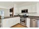 Well-lit kitchen with white cabinets, stainless steel appliances, granite counters, and an open layout to the living area at 10758 Gettysburg Pl, Carmel, IN 46032