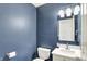 A powder room features dark blue walls, a white vanity and lighting at 10758 Gettysburg Pl, Carmel, IN 46032